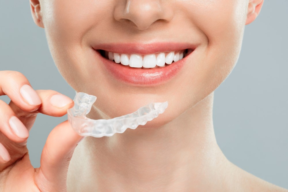 woman-holds-her-hand-removable-invisible-transparent-aligners-smiles